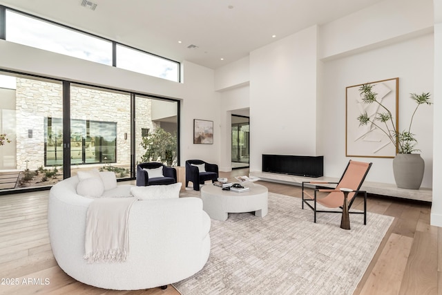 living room with visible vents, recessed lighting, a high ceiling, and wood finished floors