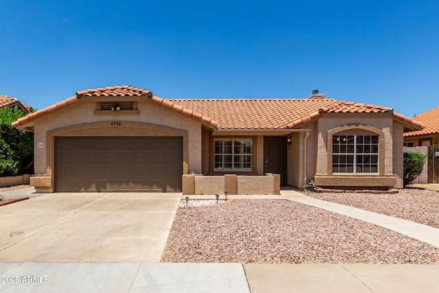 4336 E Aspen Ave, Mesa, AZ 85201 - mediterranean / spanish home featuring a garage, concrete driveway, a tiled roof, and stucco siding