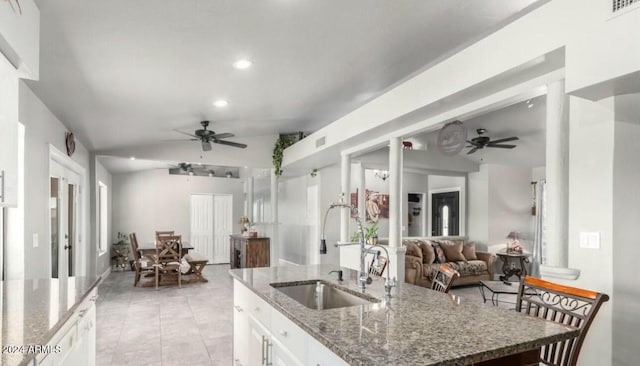 kitchen featuring lofted ceiling, dark stone counters, sink, ceiling fan, and white cabinetry