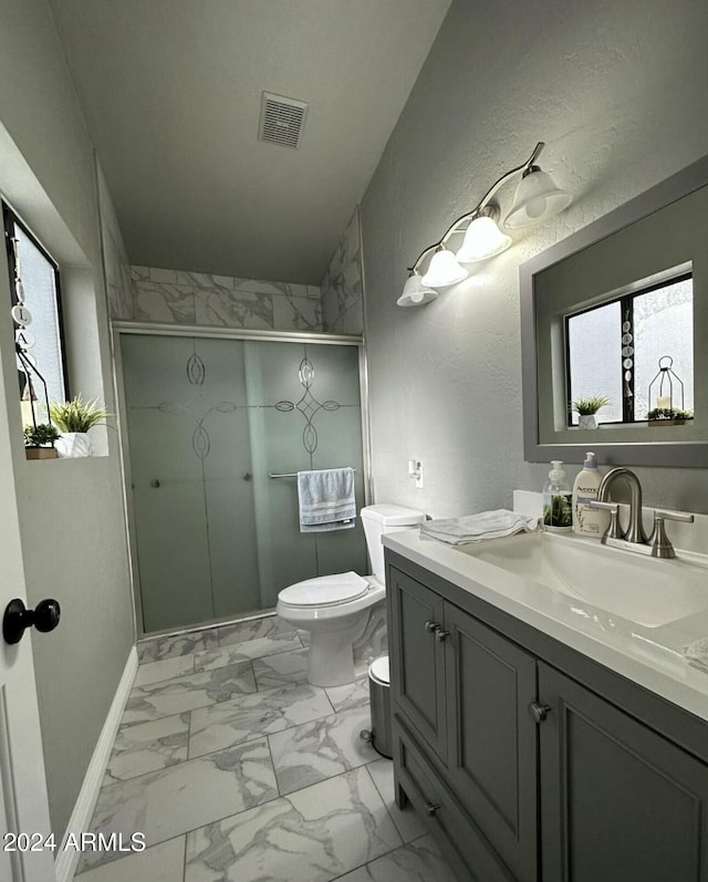 bathroom with vanity, toilet, and a shower with door