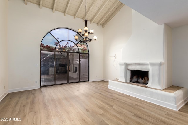 unfurnished living room featuring wood ceiling, a chandelier, light wood-type flooring, beamed ceiling, and high vaulted ceiling