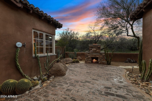 patio terrace at dusk featuring an outdoor stone fireplace