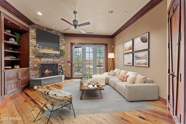 living room with ceiling fan, light hardwood / wood-style floors, a fireplace, and crown molding