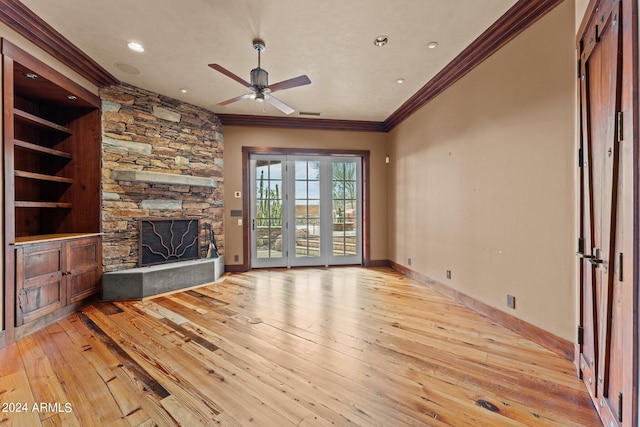 unfurnished living room featuring ceiling fan, a stone fireplace, ornamental molding, and light hardwood / wood-style floors