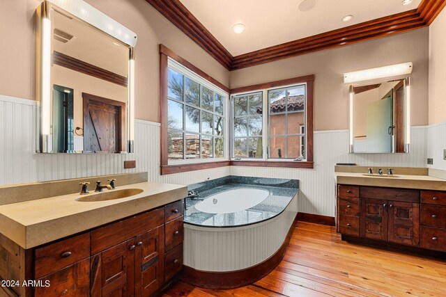 bathroom with crown molding, a bathtub, hardwood / wood-style floors, and double sink vanity