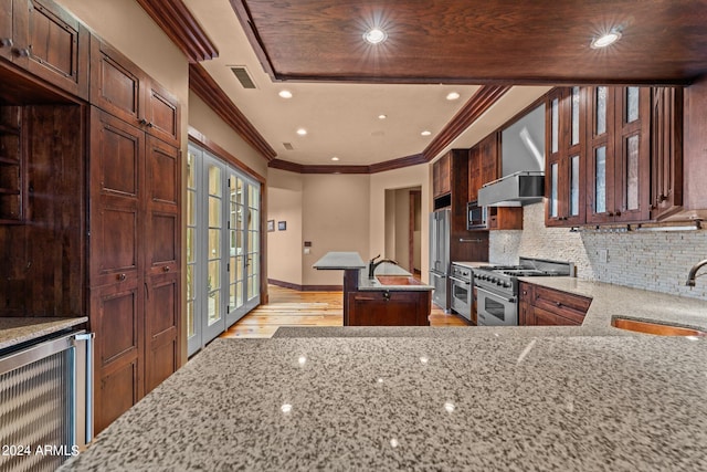 kitchen with light hardwood / wood-style floors, stainless steel appliances, wall chimney exhaust hood, beverage cooler, and tasteful backsplash