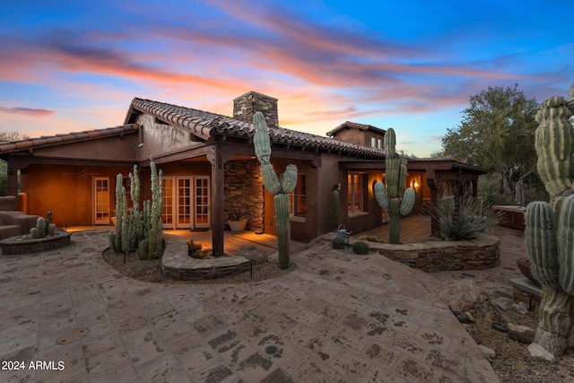 back house at dusk featuring french doors and a patio