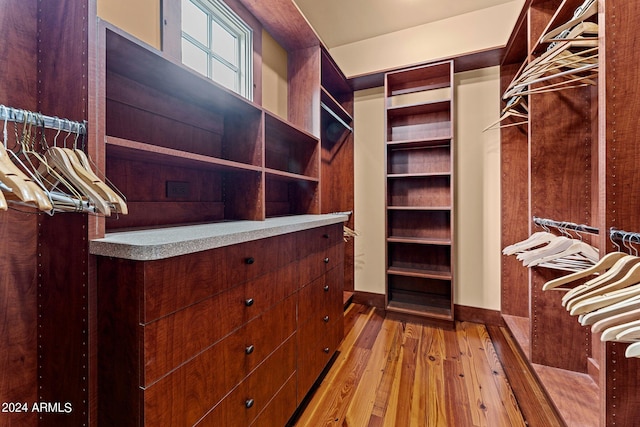 walk in closet with light hardwood / wood-style floors