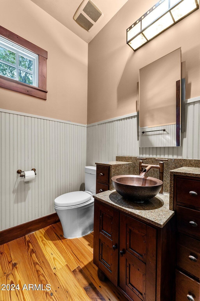 bathroom with wood-type flooring, vanity with extensive cabinet space, and toilet