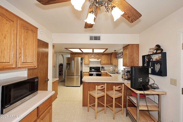 kitchen featuring ceiling fan, appliances with stainless steel finishes, kitchen peninsula, and sink