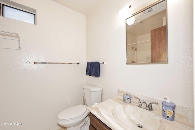 bathroom featuring toilet, vanity, and a shower