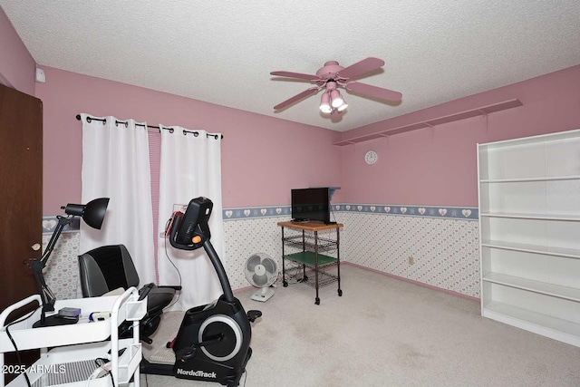 workout room featuring light carpet, ceiling fan, and a textured ceiling