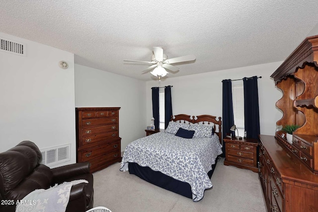 bedroom with a textured ceiling, ceiling fan, and light colored carpet