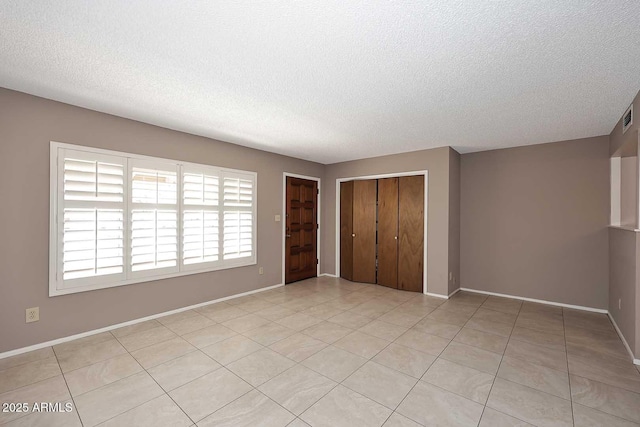 unfurnished bedroom featuring a textured ceiling, a closet, and light tile patterned floors