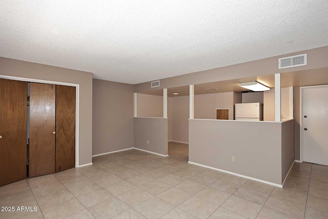 empty room featuring a textured ceiling and light tile patterned flooring