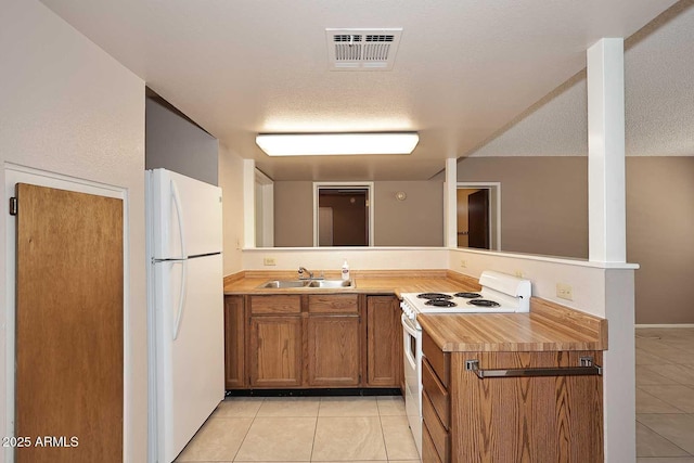 kitchen featuring sink, light tile patterned flooring, white appliances, and a textured ceiling