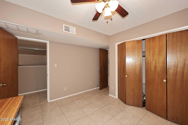 unfurnished bedroom featuring a textured ceiling, ceiling fan, and light tile patterned floors