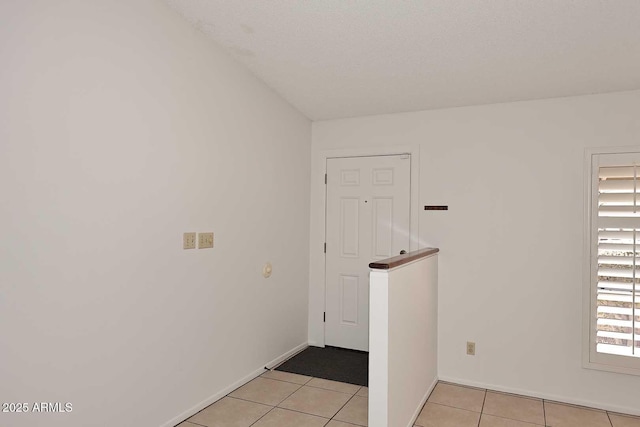 unfurnished room with a textured ceiling and light tile patterned floors