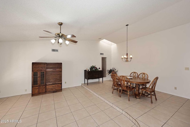 tiled dining room with a textured ceiling, ceiling fan with notable chandelier, and high vaulted ceiling