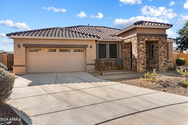 mediterranean / spanish home featuring stucco siding, a tiled roof, driveway, and a garage