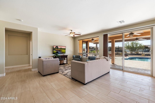 living room with baseboards, visible vents, and a ceiling fan