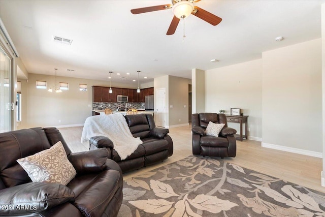 living room with ceiling fan with notable chandelier and light wood-type flooring