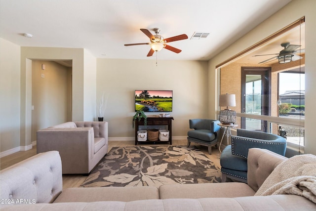 living room featuring a ceiling fan, visible vents, wood finished floors, and baseboards