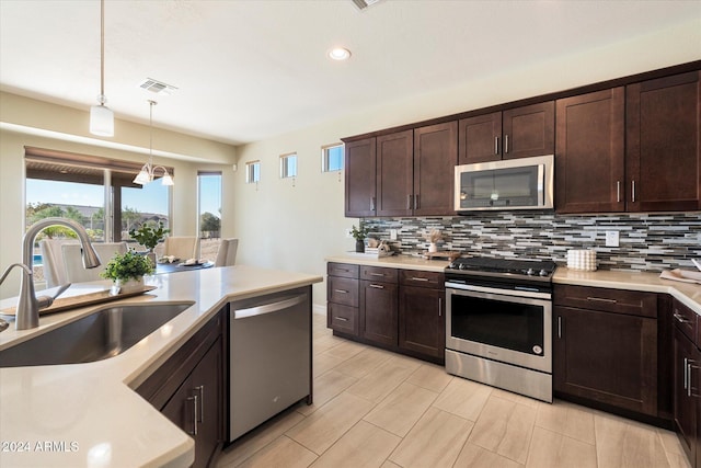 kitchen with dark brown cabinetry, stainless steel appliances, backsplash, and a sink