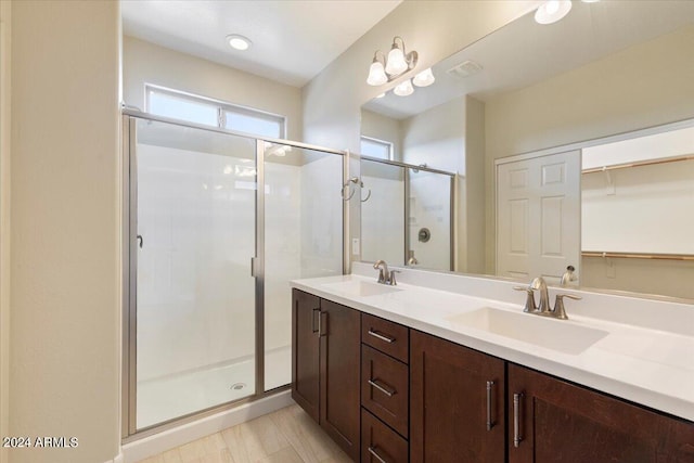 bathroom featuring a shower with door and vanity