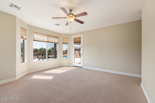 empty room with visible vents, ceiling fan, and light colored carpet