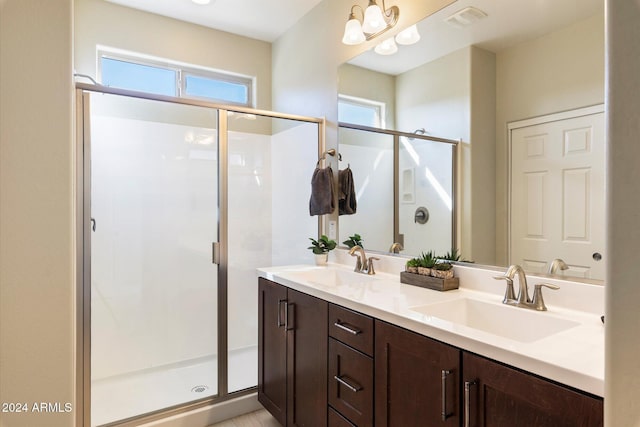 bathroom with visible vents, a shower stall, double vanity, and a sink