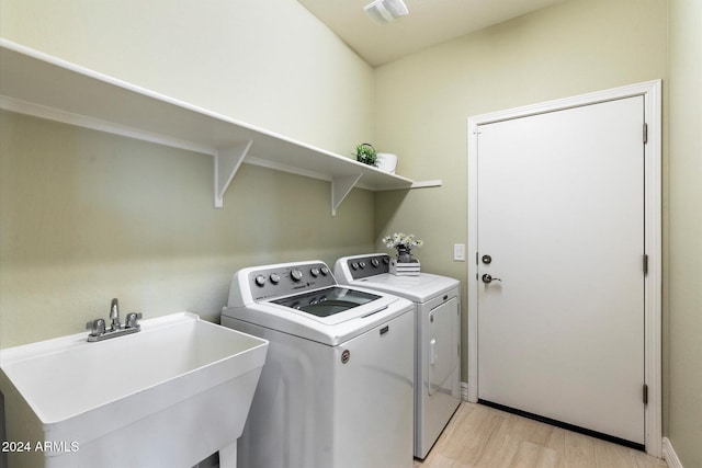 laundry area featuring light wood finished floors, a sink, separate washer and dryer, laundry area, and visible vents