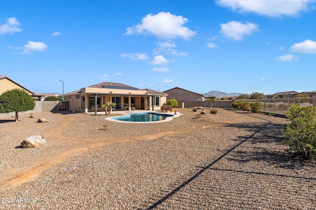 rear view of property with a fenced backyard, solar panels, a fenced in pool, and a patio area