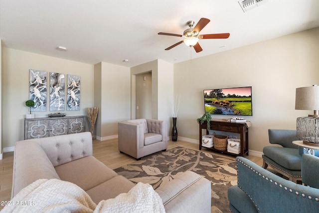 living room with a ceiling fan, visible vents, wood finished floors, and baseboards