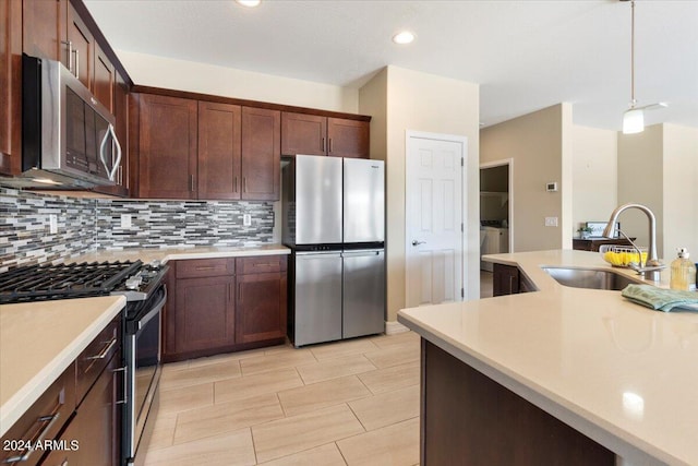 kitchen with decorative backsplash, dark brown cabinetry, decorative light fixtures, sink, and stainless steel appliances