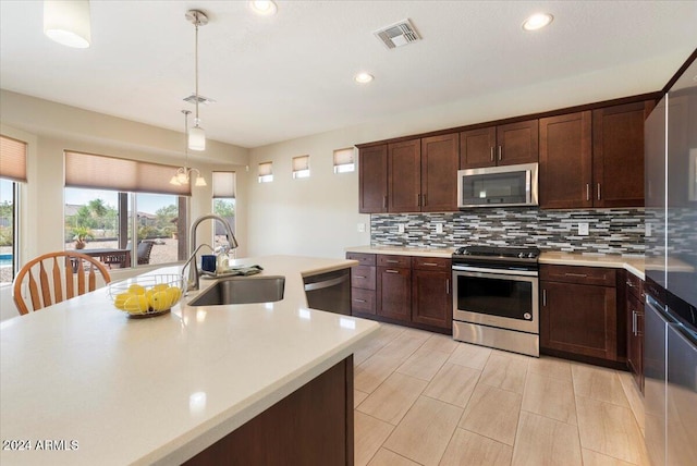 kitchen featuring dark brown cabinetry, hanging light fixtures, sink, appliances with stainless steel finishes, and decorative backsplash