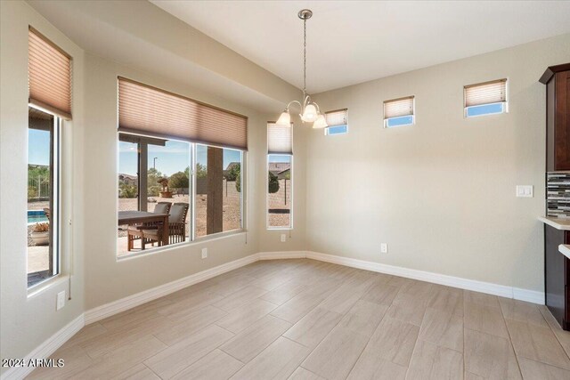 unfurnished dining area with an inviting chandelier, light hardwood / wood-style floors, and a wealth of natural light