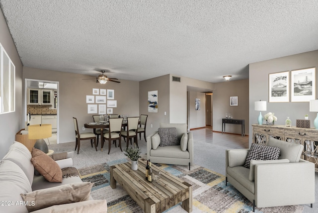 carpeted living room featuring ceiling fan and a textured ceiling