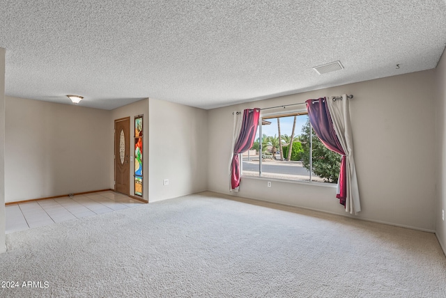 unfurnished room with light carpet and a textured ceiling