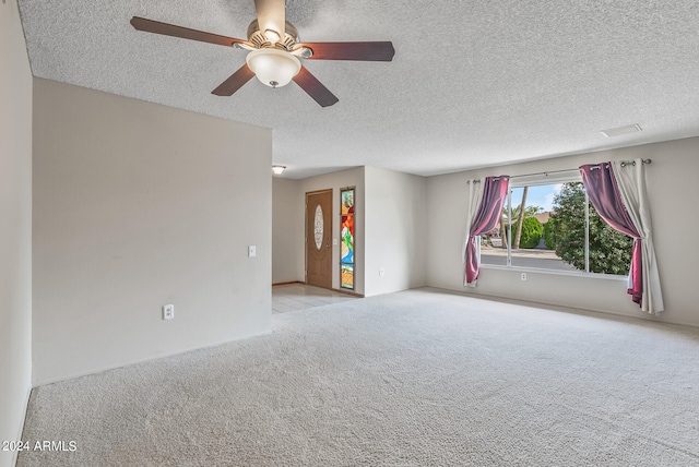 unfurnished room with light carpet, ceiling fan, and a textured ceiling