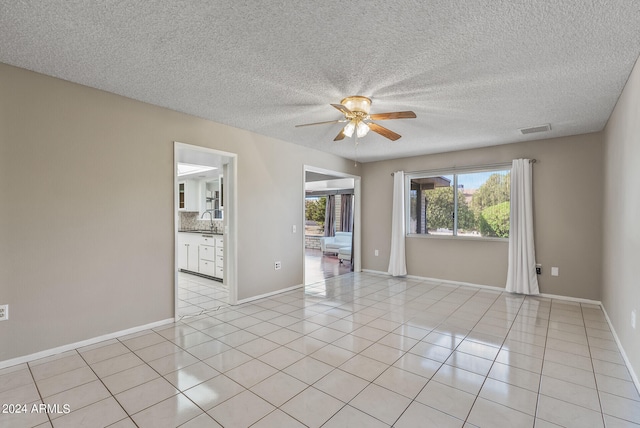 unfurnished room with sink, a textured ceiling, ceiling fan, and light tile patterned flooring