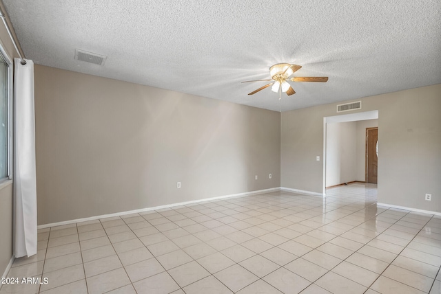 tiled empty room with ceiling fan and a textured ceiling