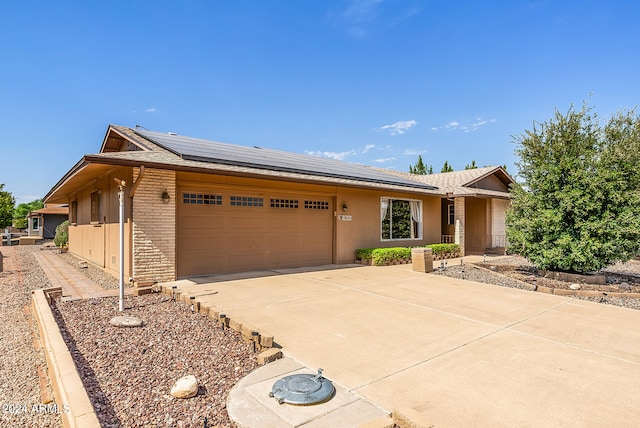 ranch-style home featuring solar panels and a garage