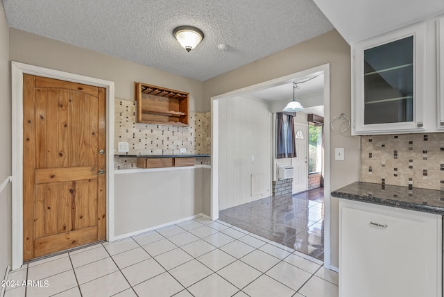 kitchen with tasteful backsplash, white cabinets, pendant lighting, a textured ceiling, and light tile patterned flooring