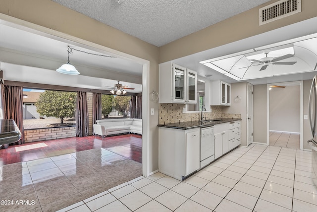 kitchen featuring dishwasher, sink, a textured ceiling, light tile patterned flooring, and white cabinetry