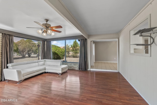 unfurnished living room with ceiling fan, beamed ceiling, and hardwood / wood-style flooring