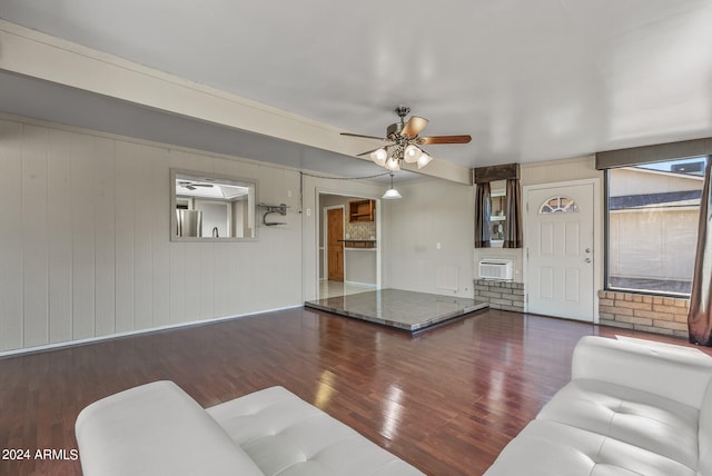 living room featuring a wall mounted AC, ceiling fan, wooden walls, and dark wood-type flooring