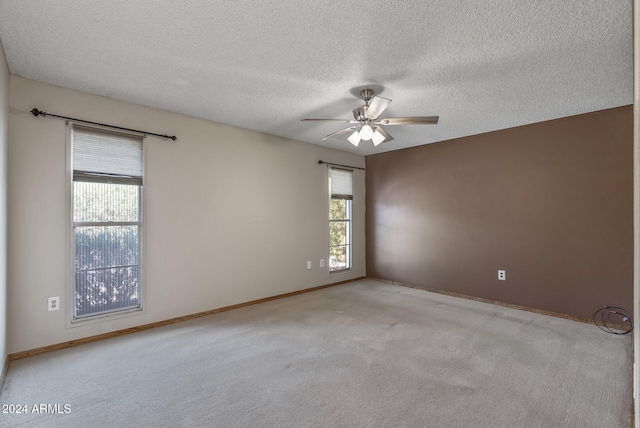 empty room with ceiling fan, a textured ceiling, and light carpet