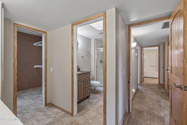 hall with a textured ceiling and light tile patterned flooring