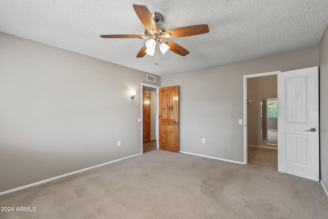 unfurnished bedroom with a textured ceiling, ceiling fan, and light carpet